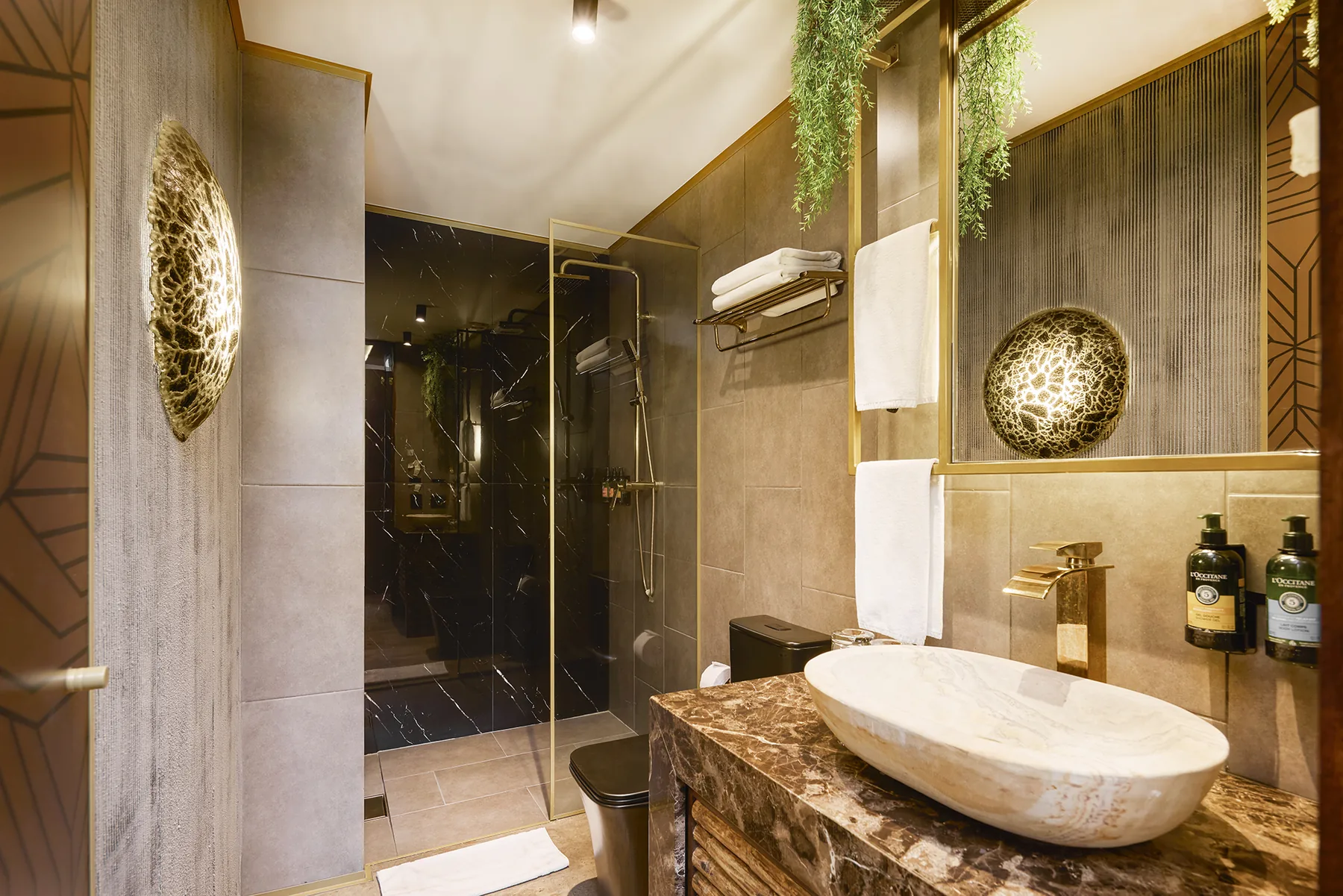 Baño con ducha de mármol negro y grifería dorada