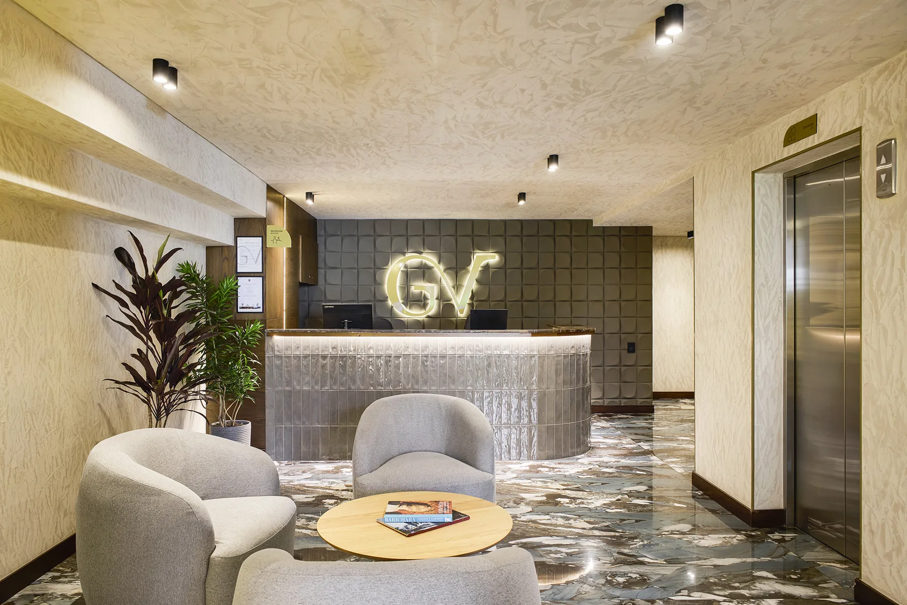 Recepción de Golden Valley Hotel con el monograma GV retroiluminado